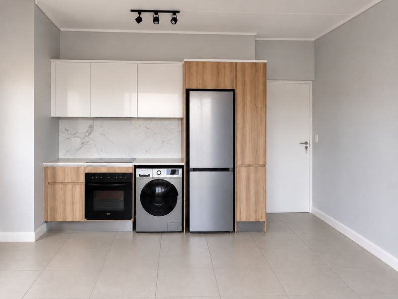 Modern kitchen featuring sleek white and wood-grain cabinetry, marble-look splashback, integrated oven, hob, and tiled flooring in a clean, contemporary open-plan space.