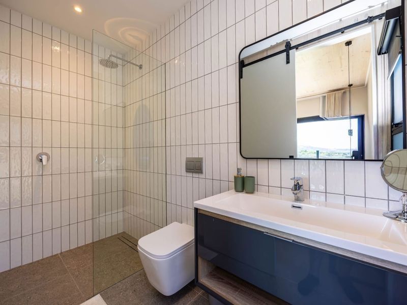 Modern bathroom featuring a walk-in shower with glass screen, wall-mounted toilet, and a sleek vanity unit with integrated basin.