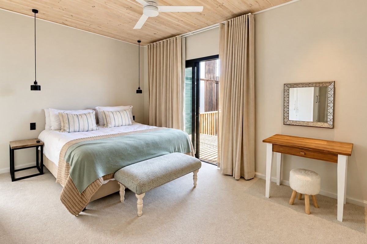 A well-maintained bedroom featuring a timber ceiling, ceiling fan, carpeted flooring, and a sliding glass door providing access to an outdoor area.