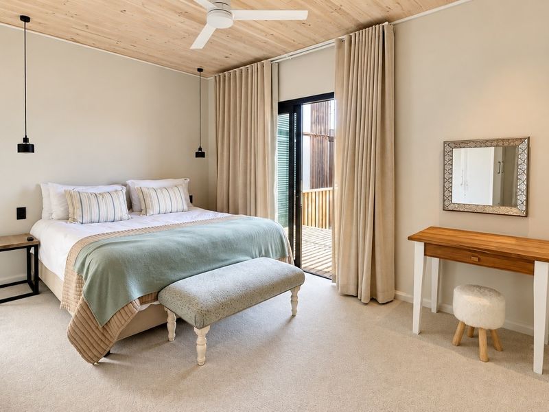 A well-maintained bedroom featuring a timber ceiling, ceiling fan, carpeted flooring, and a sliding glass door providing access to an outdoor area.