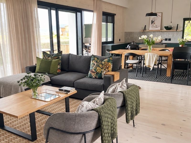 Spacious open-plan living and dining area featuring timber flooring, modern kitchen cabinetry, and large sliding glass doors leading to the outdoor space.