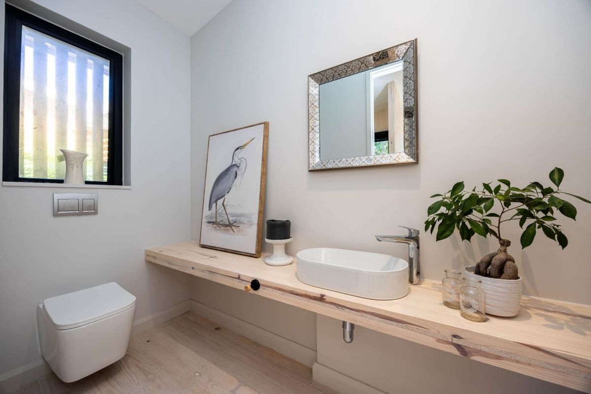 Modern guest bathroom featuring a wall-hung toilet, timber vanity shelf with a sleek countertop basin, and contemporary chrome fixtures.