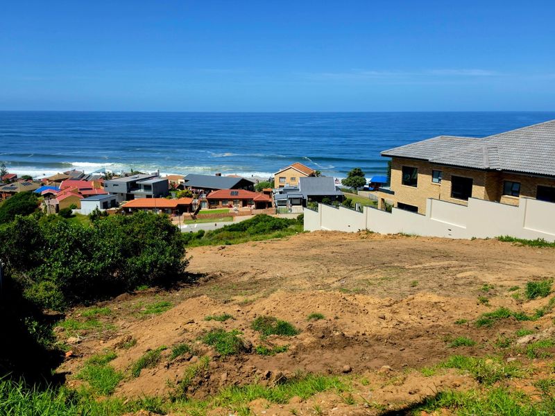 Elevated view of a vacant residential plot overlooking the ocean and surrounding coastal neighborhood.