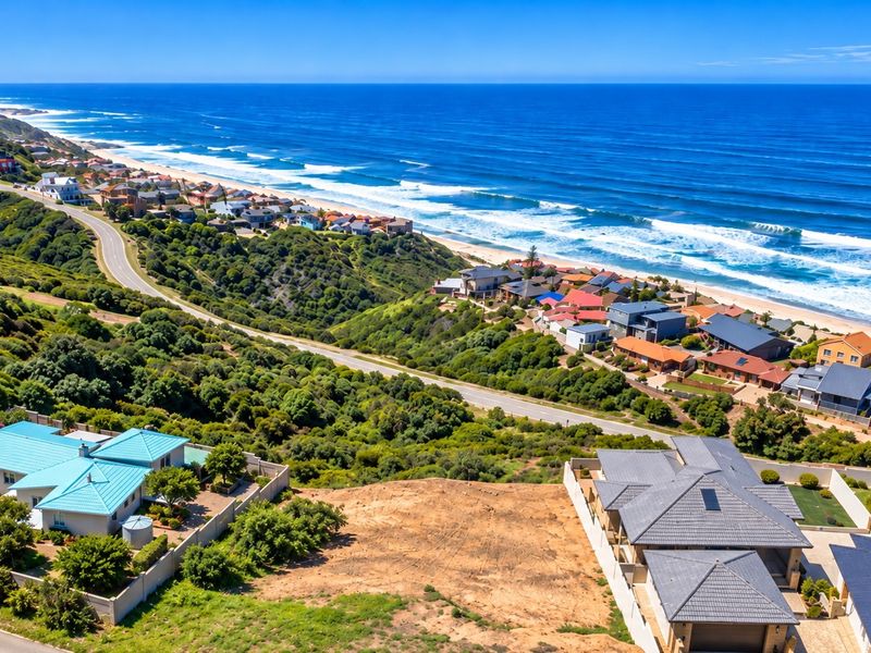 An aerial view of a vacant residential plot situated in a coastal neighborhood with expansive ocean views.