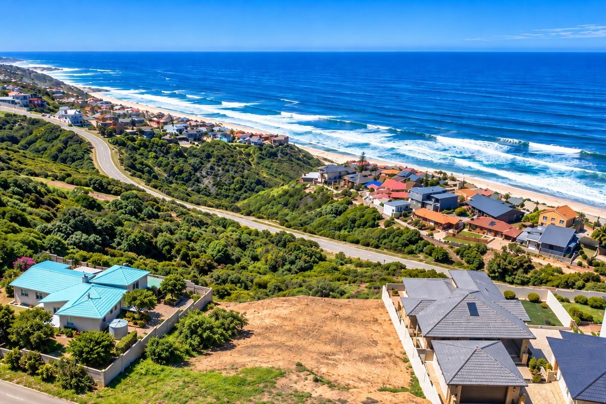 An aerial view of a vacant residential plot situated in a coastal neighborhood with expansive ocean views.