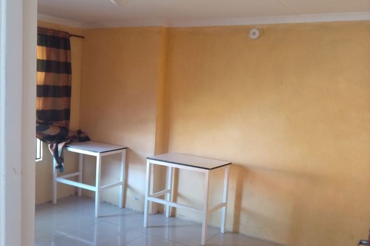 A simple, empty bedroom featuring tiled flooring and yellow painted walls, offering a blank canvas for potential interior design updates.