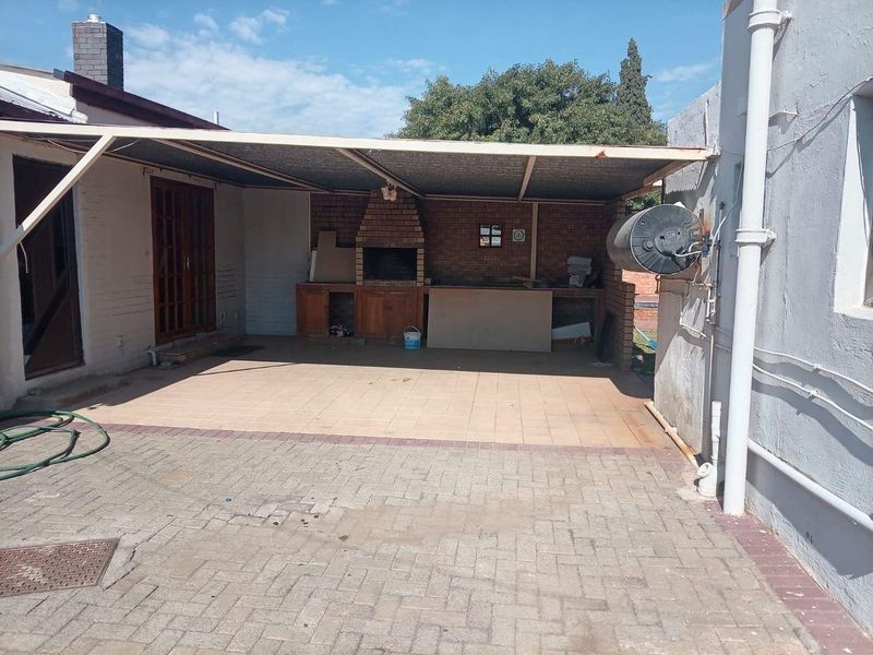 Covered outdoor patio area featuring a built-in brick braai, tiled flooring, and direct access to the main dwelling.