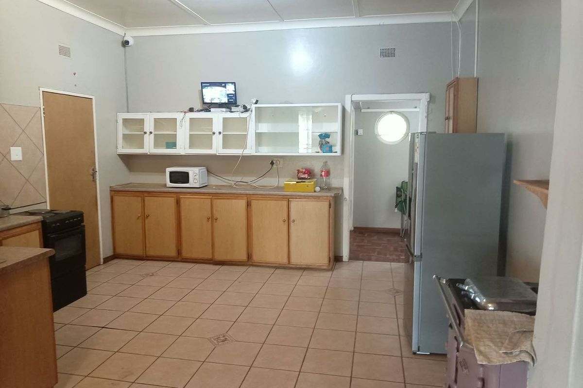 A functional kitchen featuring tiled flooring, built-in wooden cabinetry, and a freestanding stove, offering a dated layout ready for modern updates.