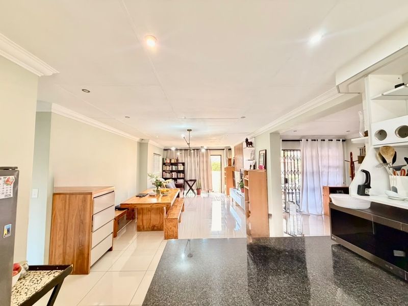 Spacious open-plan living and dining area featuring polished tiled floors, recessed lighting, and a modern kitchen with granite countertops.