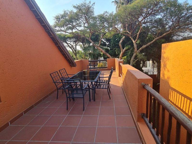 Spacious open-air balcony featuring terracotta-style floor tiles, masonry walls, and a timber handrail, offering a functional outdoor space for relaxation.