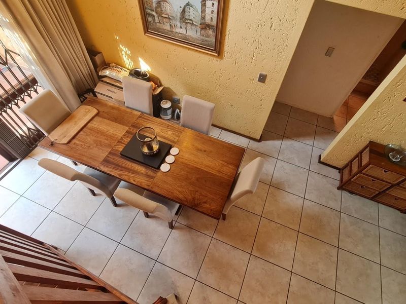 Dining area featuring ceramic floor tiles and textured walls, with direct access to an outdoor patio through a security gate.