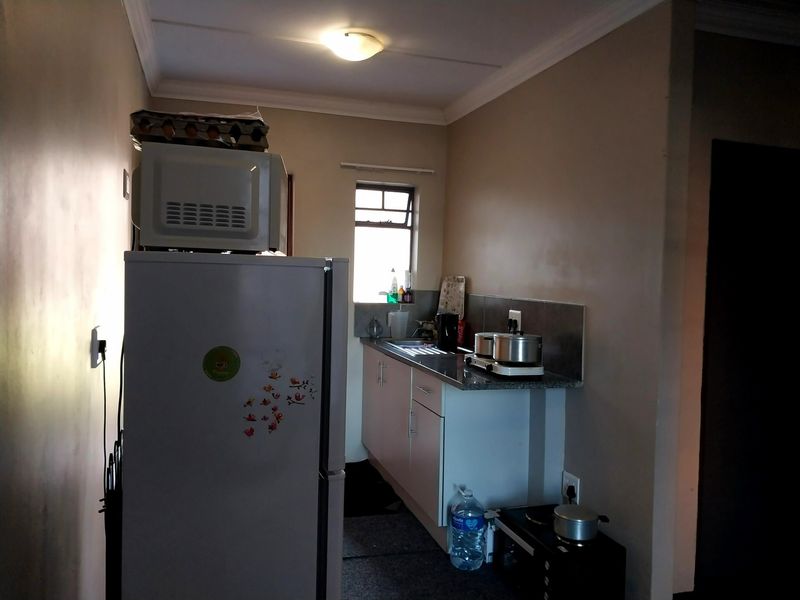 A compact kitchen area featuring functional cabinetry, a countertop with a sink, and a tiled splashback, providing essential food preparation space.