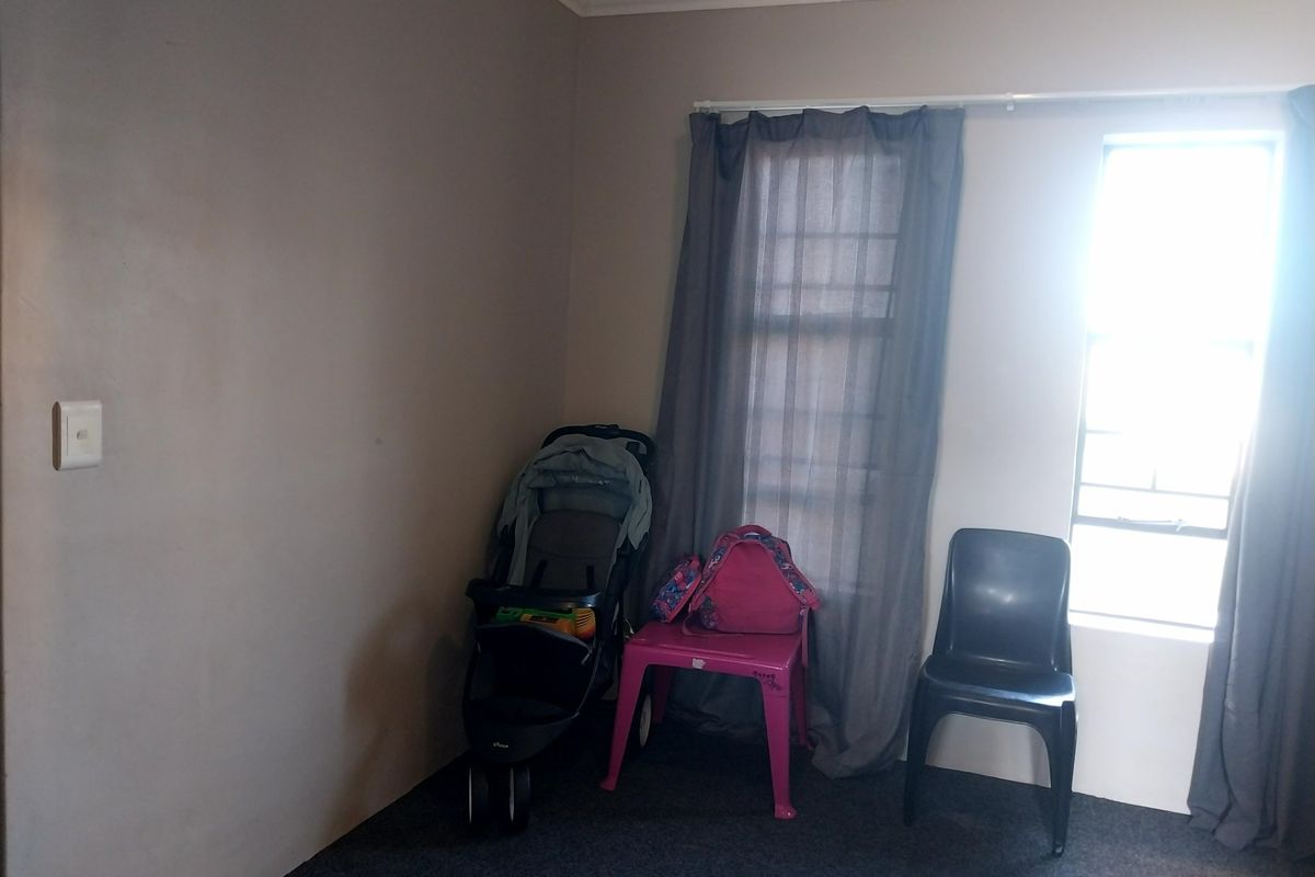 A simple bedroom featuring carpeted flooring, a window with curtains, and coving detail.