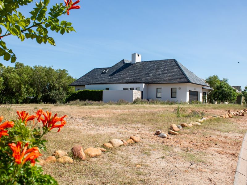 A view of the front elevation of a residential property featuring a slate roof, stone accents, and a garage, set on a large plot.