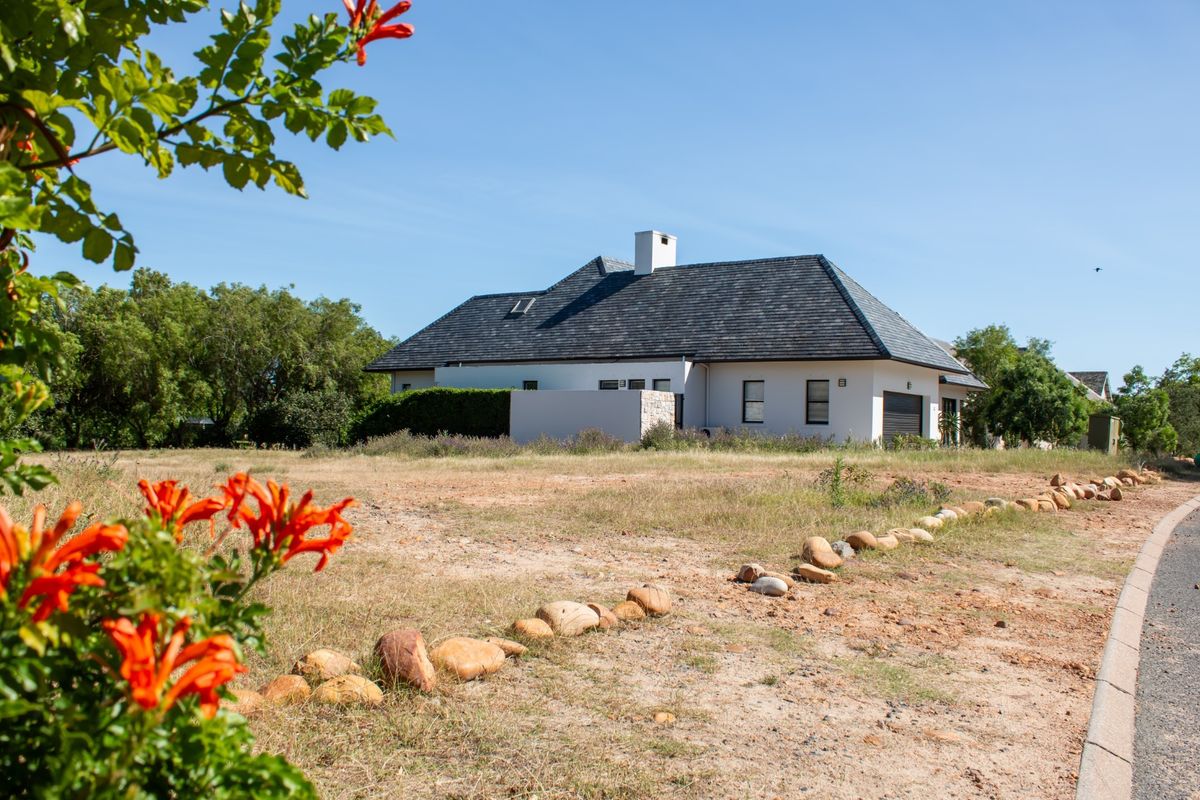 A view of the front elevation of a residential property featuring a slate roof, stone accents, and a garage, set on a large plot.