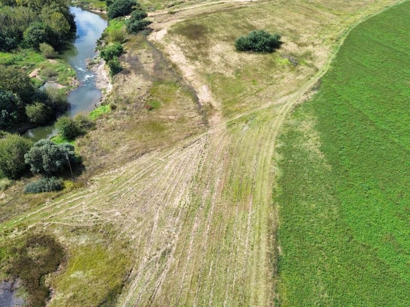 An aerial view of the farm property showcasing extensive open fields, cultivated land, and natural river frontage.