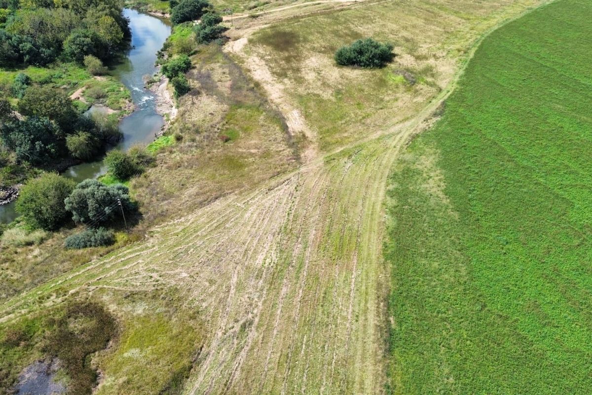 An aerial view of the farm property showcasing extensive open fields, cultivated land, and natural river frontage.