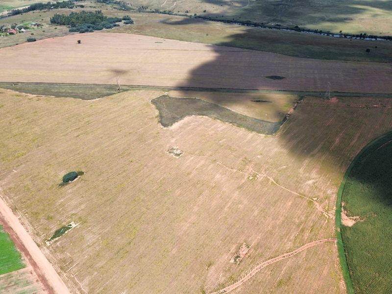 An aerial view of expansive agricultural farmland, showcasing open fields and rural landscape features suitable for farming operations.