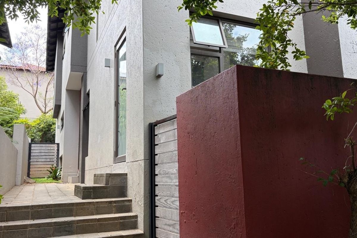 A side pathway featuring concrete steps, textured exterior walls, and a red feature wall leading towards the rear of the property.