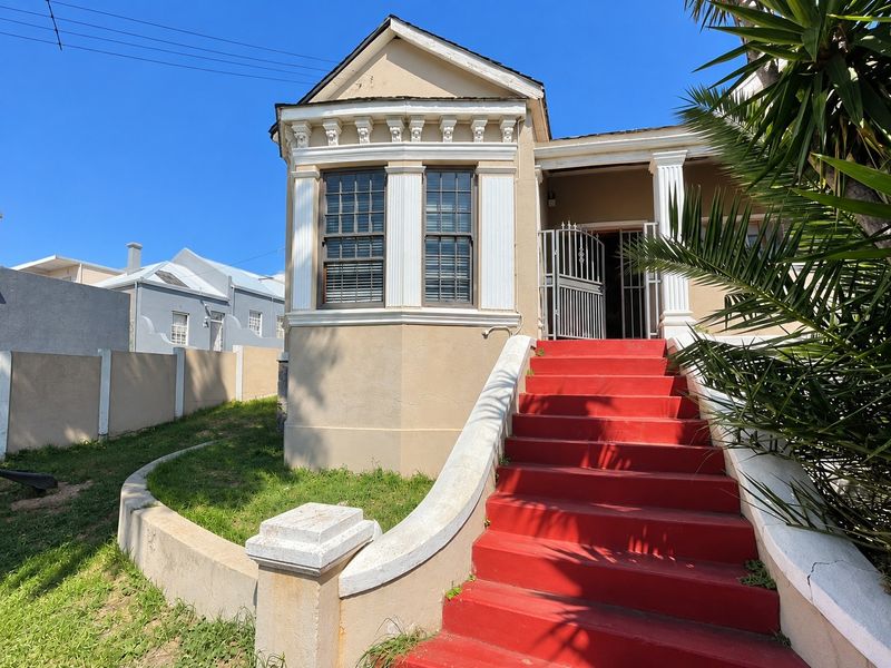 Front elevation of a character home featuring a prominent red staircase, decorative architectural detailing, and a secure entrance gate.