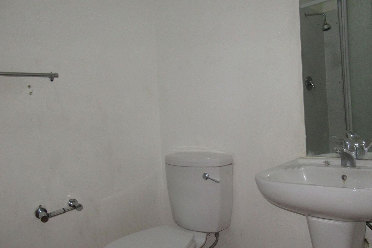 A functional bathroom featuring a pedestal basin, toilet, and shower enclosure, requiring cosmetic updates to improve its overall condition and appeal.