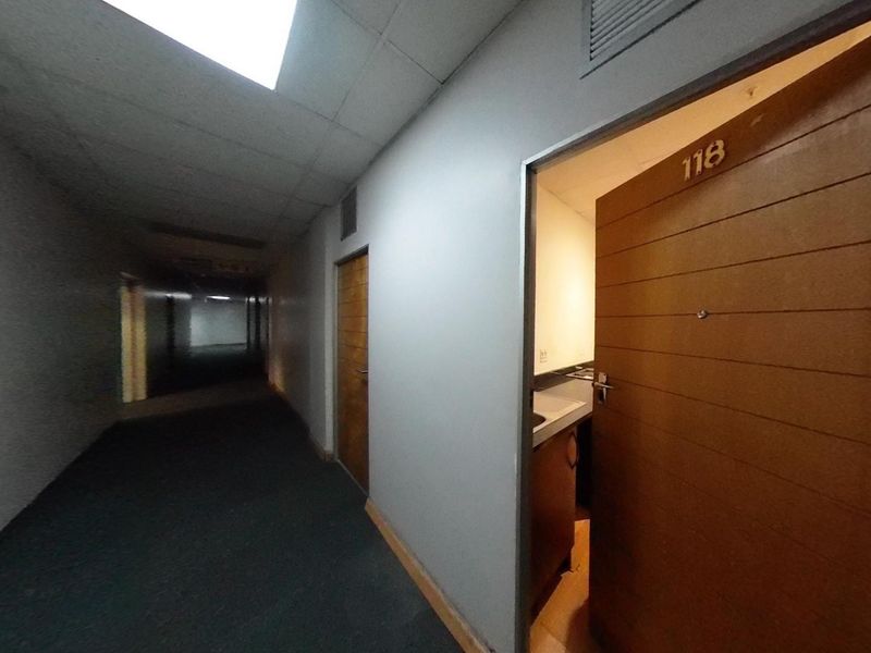 A view of a dimly lit apartment building hallway with carpeted flooring and access to unit 118.