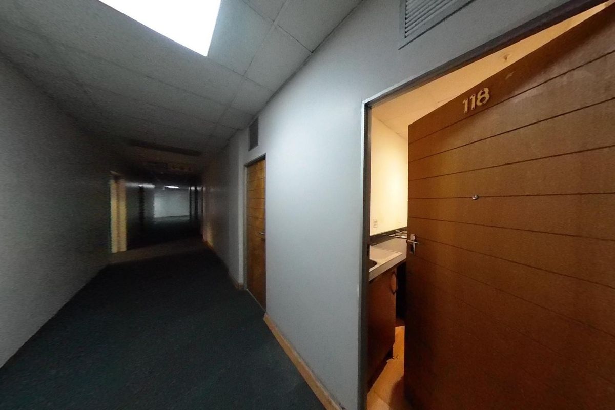 A view of a dimly lit apartment building hallway with carpeted flooring and access to unit 118.