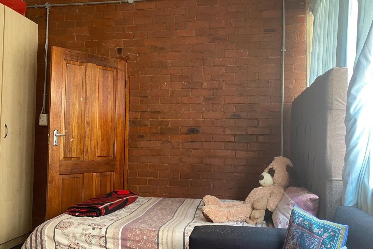 A bedroom featuring an exposed brick feature wall and exposed electrical conduit, offering a rustic industrial aesthetic.