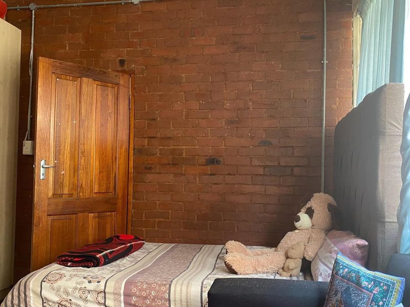 A bedroom featuring an exposed brick feature wall and exposed electrical conduit, offering a rustic industrial aesthetic.
