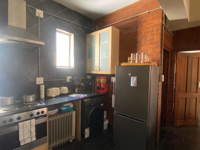 Industrial-style kitchen featuring exposed brickwork, dark tiled splashbacks, built-in oven with extractor fan, and ample cabinetry with stone countertops.