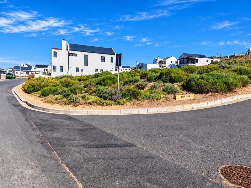 A street view of a residential estate corner featuring asphalt roads, concrete curbing, and established landscaping in a quiet neighborhood setting.