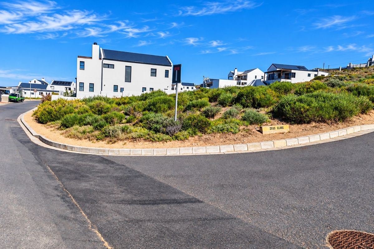 A street view of a residential estate corner featuring asphalt roads, concrete curbing, and established landscaping in a quiet neighborhood setting.