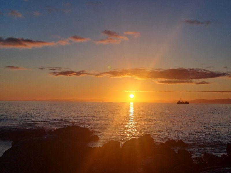 A scenic sunset view over the ocean, highlighting the coastal landscape and horizon.
