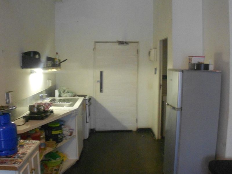 A compact kitchen area featuring basic cabinetry, a sink, and a functional layout, currently showing signs of wear and requiring cosmetic updates.