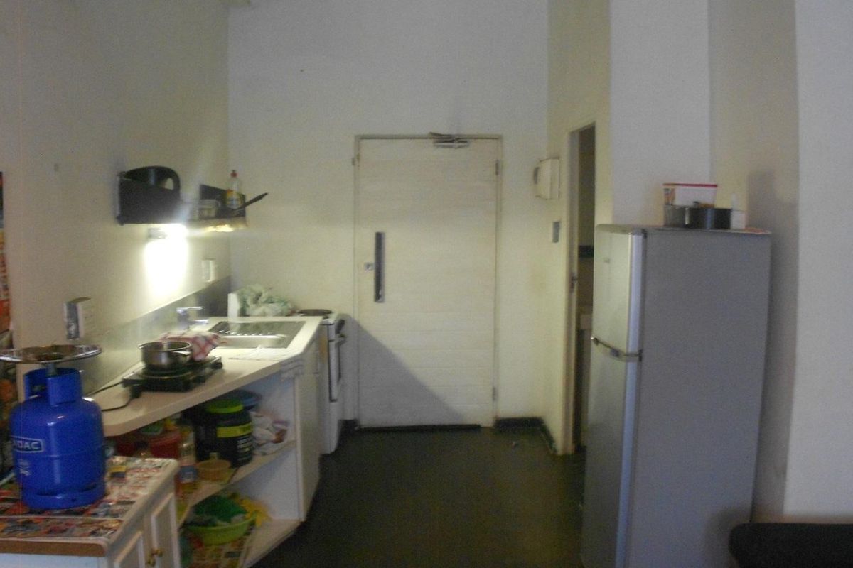 A compact kitchen area featuring basic cabinetry, a sink, and a functional layout, currently showing signs of wear and requiring cosmetic updates.