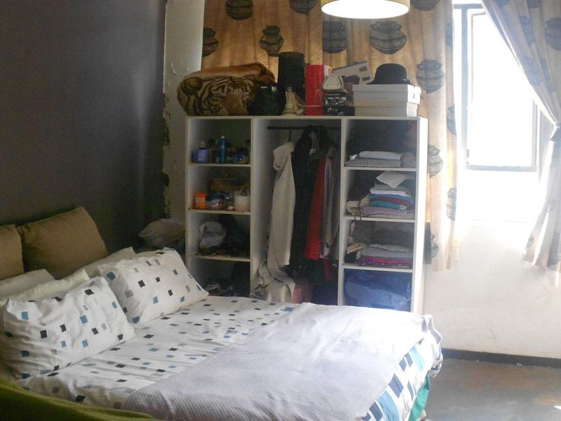 A bedroom featuring a window and wall space, currently showing signs of wear and requiring cosmetic updates.