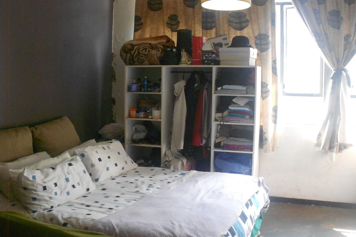 A bedroom featuring a window and wall space, currently showing signs of wear and requiring cosmetic updates.