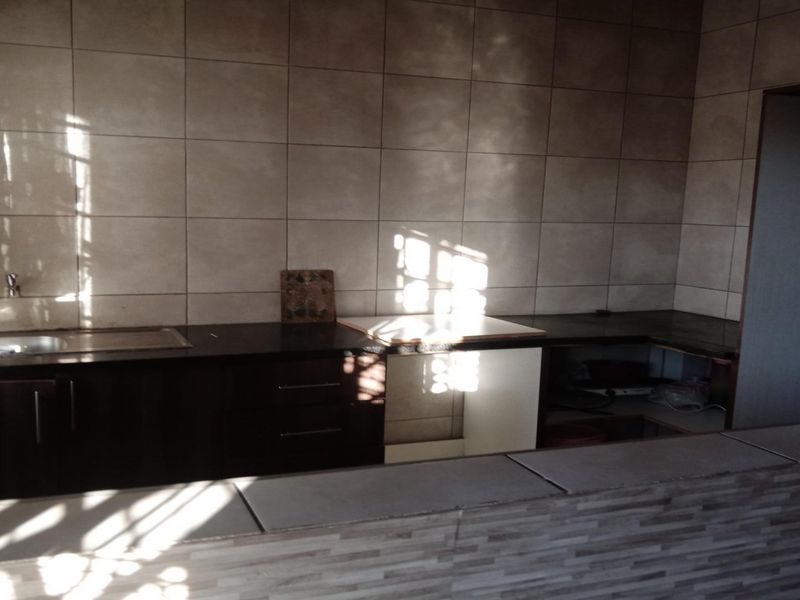 A functional kitchen featuring dark built-in cabinetry, a tiled backsplash, and a breakfast bar counter, providing a practical layout for meal preparation.