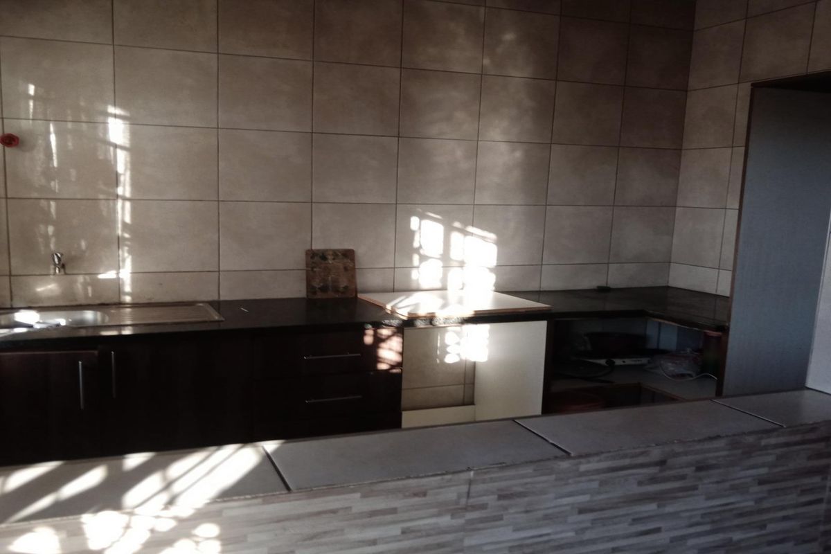 A functional kitchen featuring dark built-in cabinetry, a tiled backsplash, and a breakfast bar counter, providing a practical layout for meal preparation.