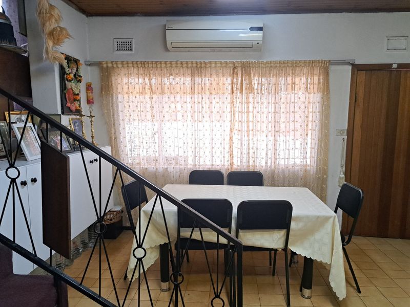 Dining area featuring tiled flooring, timber ceiling, and a wrought iron staircase railing, equipped with a wall-mounted air conditioning unit.