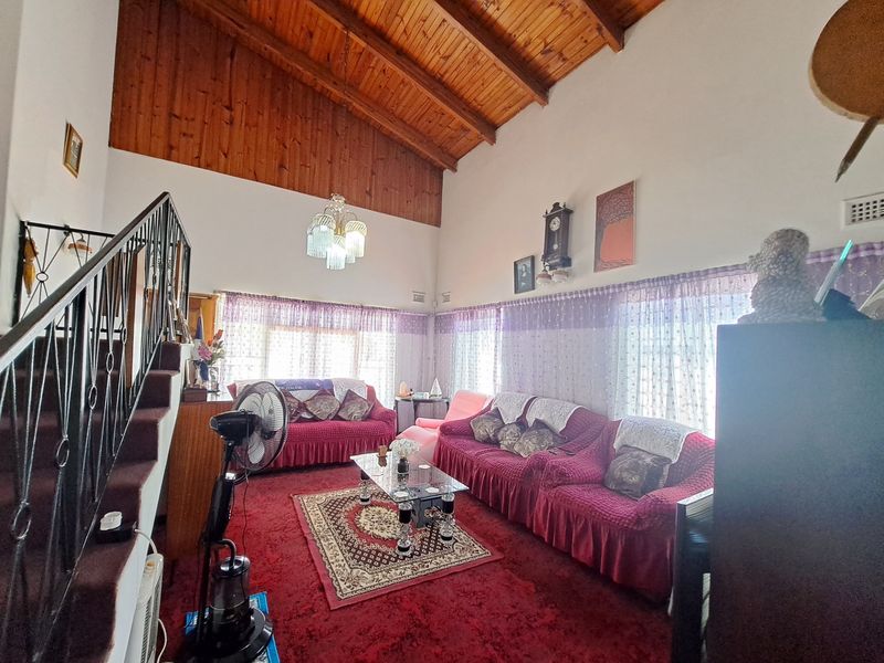 Spacious living room featuring a high exposed timber raked ceiling and a wrought iron staircase, offering a unique architectural character ready for modern updates.