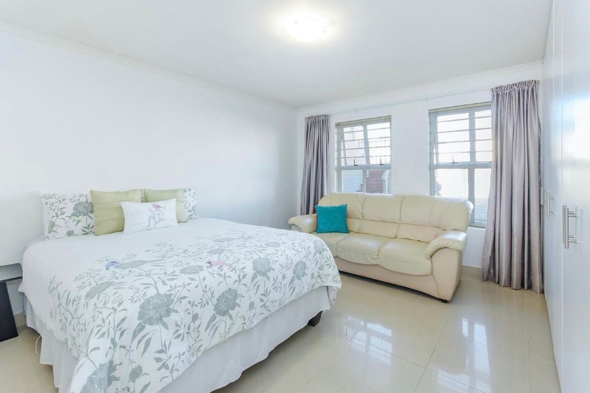 Spacious bedroom featuring neutral tiled flooring, built-in cupboards, and large windows allowing for ample natural light.
