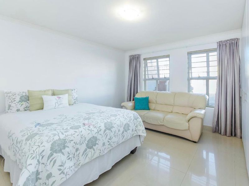 Spacious bedroom featuring neutral tiled flooring, built-in cupboards, and large windows allowing for ample natural light.
