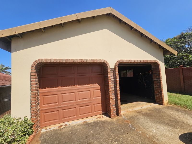A detached double garage featuring brick archways, a pitched roof, and a concrete driveway.