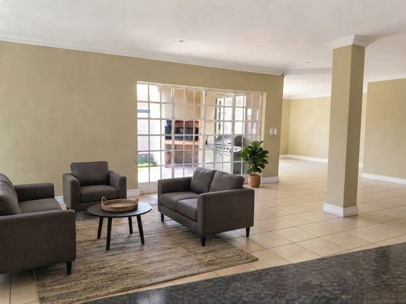 Spacious open-plan living area featuring neutral walls, tiled flooring, and large french doors providing natural light and access to the outdoor patio area.