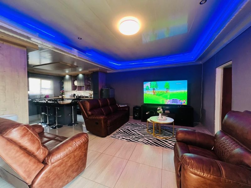 Open plan living area featuring a kitchen with island and integrated cabinetry, complemented by tiled flooring and decorative ceiling lighting.