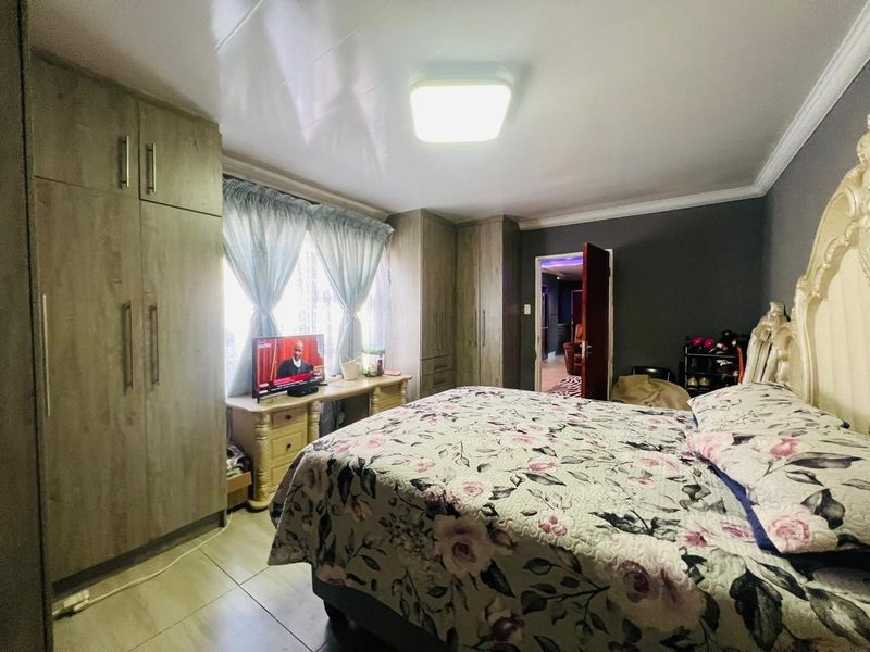 A bedroom featuring built-in wooden cupboards, tiled flooring, and a central ceiling light fixture.