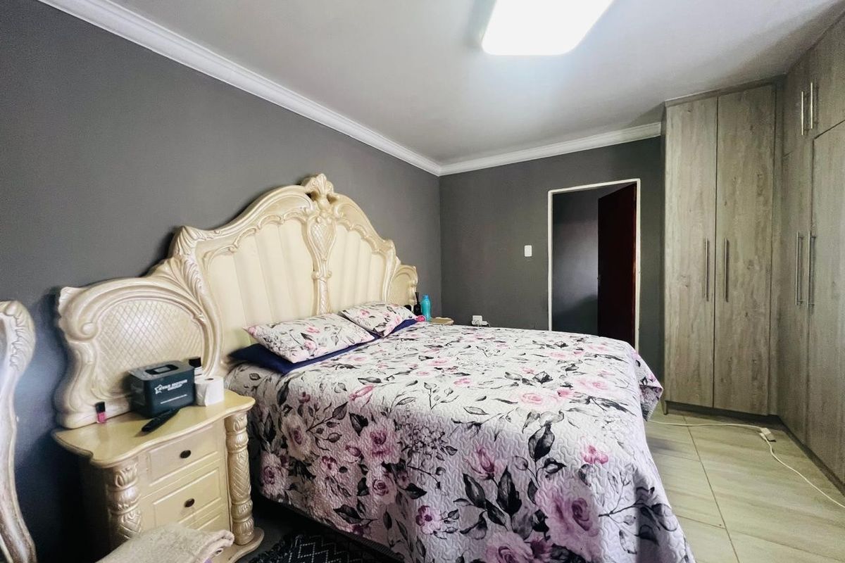 A well-maintained bedroom featuring built-in cupboards, tiled flooring, and neutral grey wall finishes.