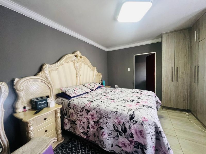 A well-maintained bedroom featuring built-in cupboards, tiled flooring, and neutral grey wall finishes.