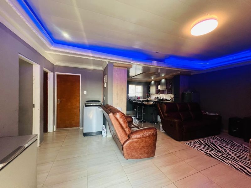 Open-plan living area featuring tiled floors, recessed ceiling lighting, and an integrated kitchen space with a central island.